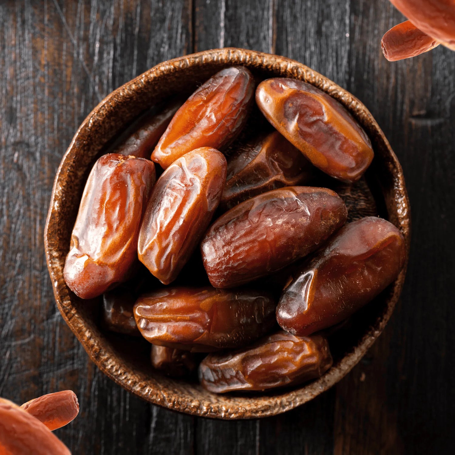 Nahaufnahme von saftigen Medjool Datteln in einer rustikalen Holzschale auf dunklem Holztisch – 100 % natürliche Premium-Datteln